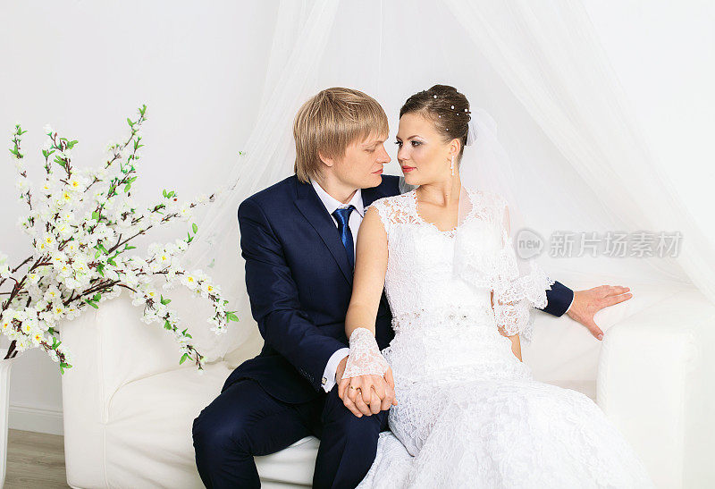 浪漫感性的新婚夫妇在豪华沙发上摆姿势