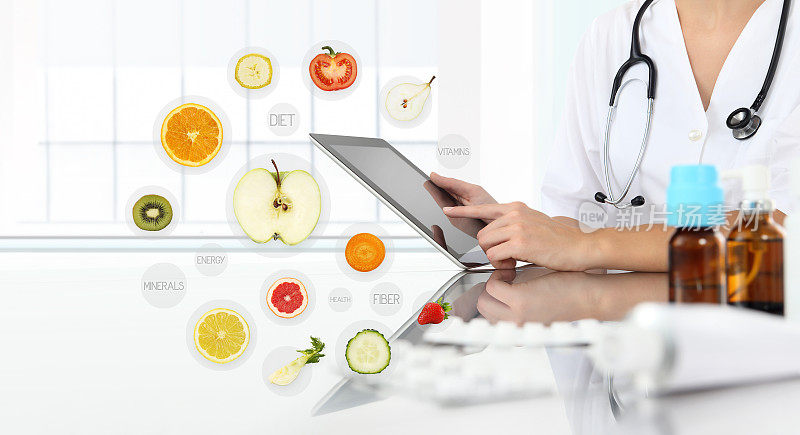 健康食品补品概念，营养师医生手触数码平板上象征水果背景