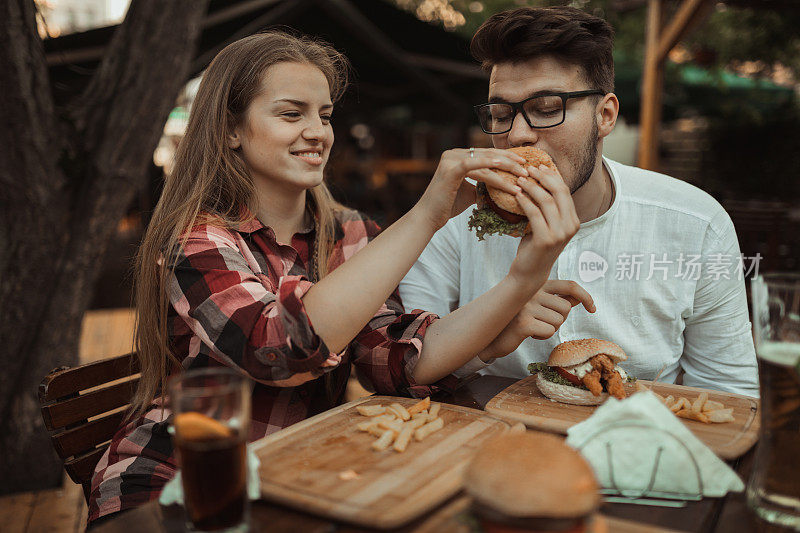 幸福的夫妇在餐厅里玩得很开心，吃着汉堡