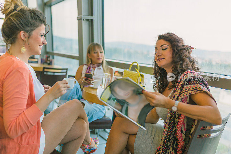 镜头拉近了三个年轻女人在咖啡桌旁喝着咖啡，