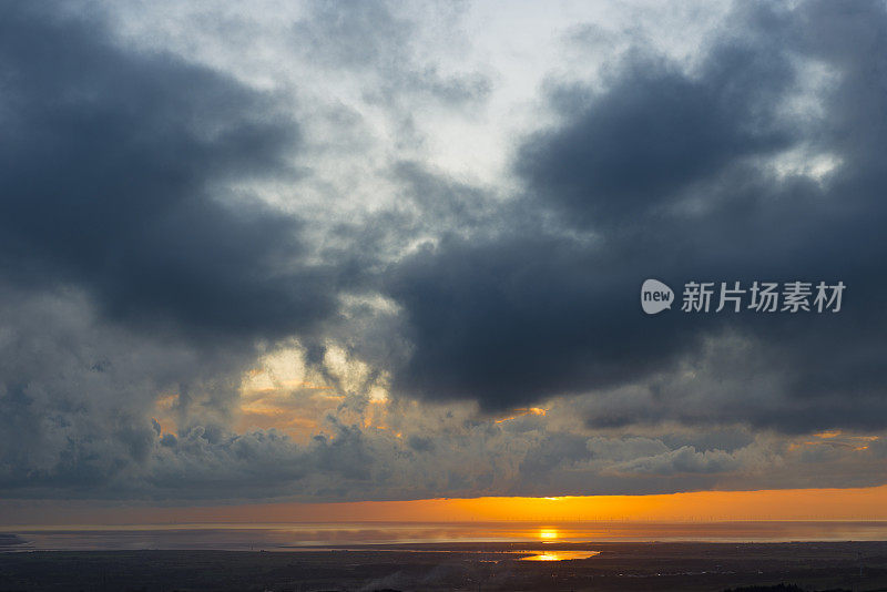 日落时分的莫克姆湾与海上风力发电场的景色。