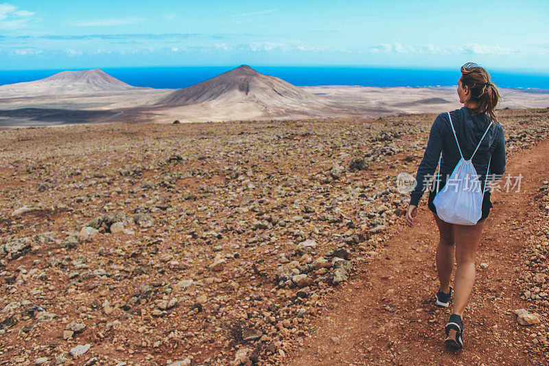 年轻女子徒步旅行与全景火山