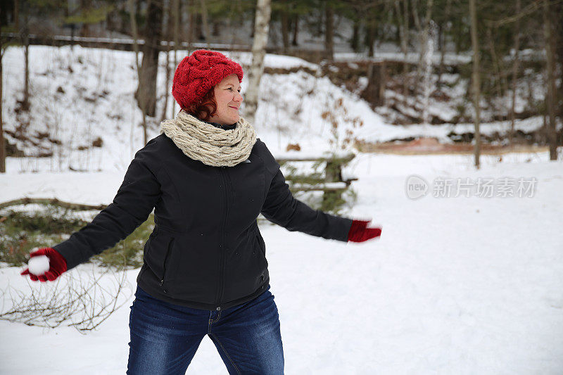 女戴针织帽，围巾，扔雪球