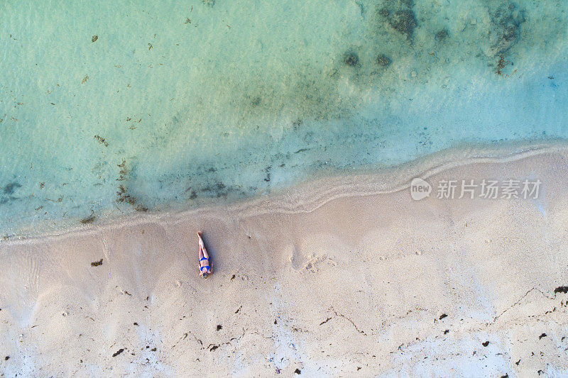 无人机拍摄的美丽的年轻女子穿着蓝色比基尼在泰国苏梅岛的一个伟大的海滩上