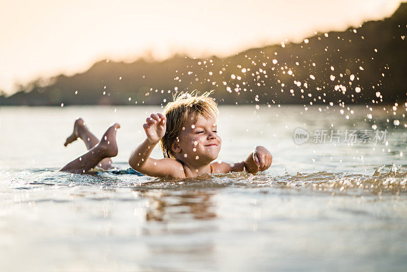 顽皮的男孩在浅水里玩在夏天的一天在海上。