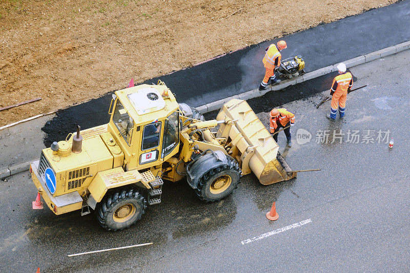 雨后的道路工程是用推土机的铲斗上的铲子铺沥青