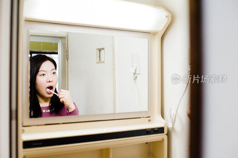 亚洲女性在浴室里通过镜子刷牙的照片