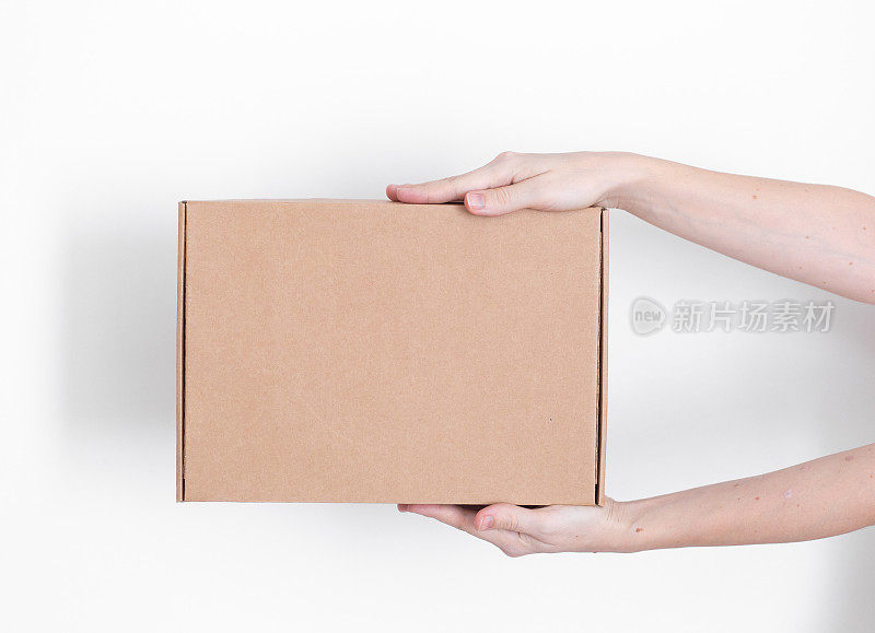 一个包裹纸箱在一个送货员的手在一个白色的背景。送货服务的概念。