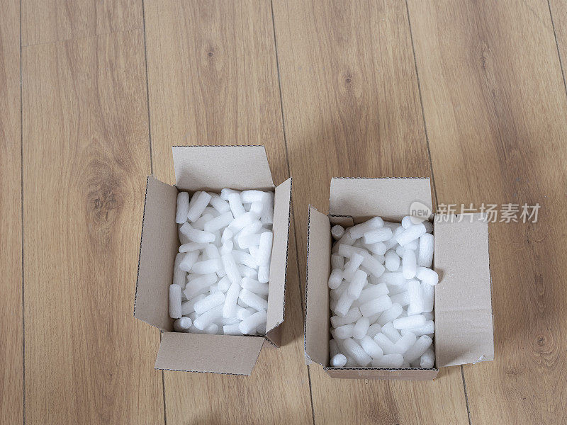 两个纸板箱与包装泡沫颗粒俯视图，在木地板上
