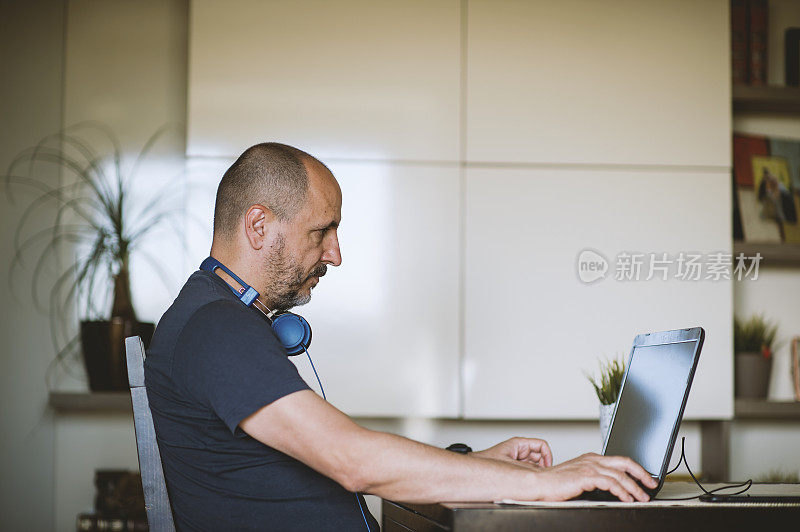 成熟的男人在家里一边听音乐一边用电脑