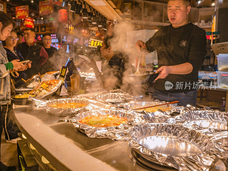 中国长沙市街头小吃巷子里的陌生人和厨师。长沙是中国湖南省的省会和人口最多的城市