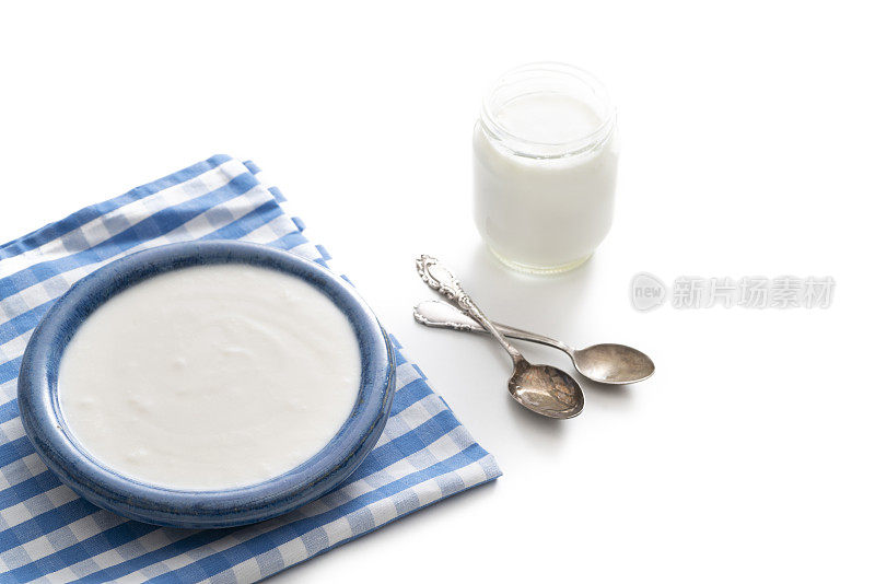 自制酸奶的蓝色碗和玻璃容器与复古勺子孤立的白色