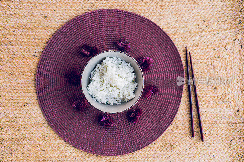 亚洲米饭和中国棍子放在一个紫色的餐垫上