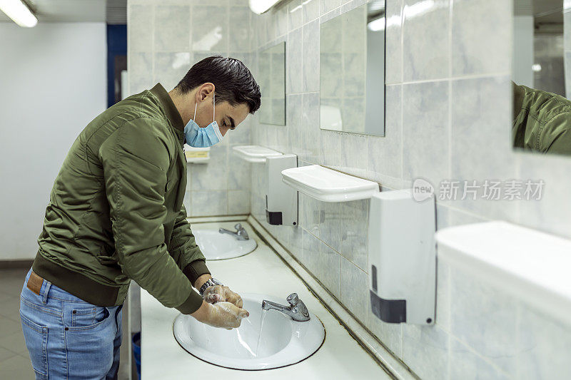 戴口罩的男子在公共卫生间洗手