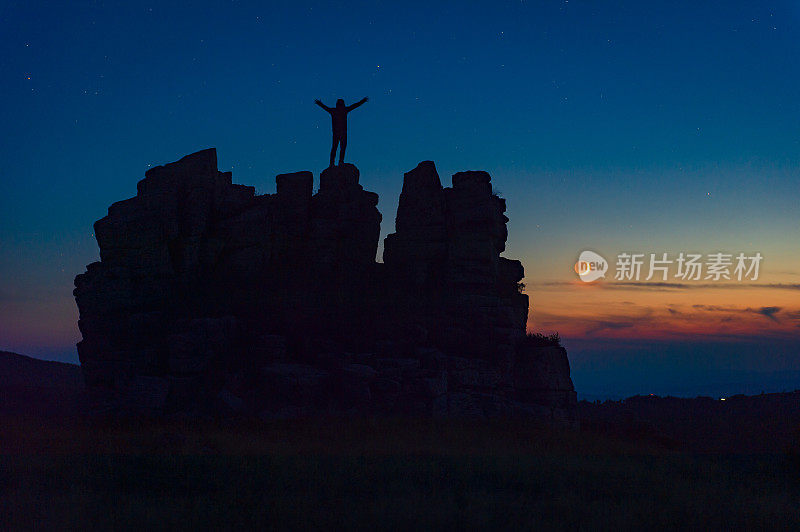 徒步旅行者站在山顶看月亮落下