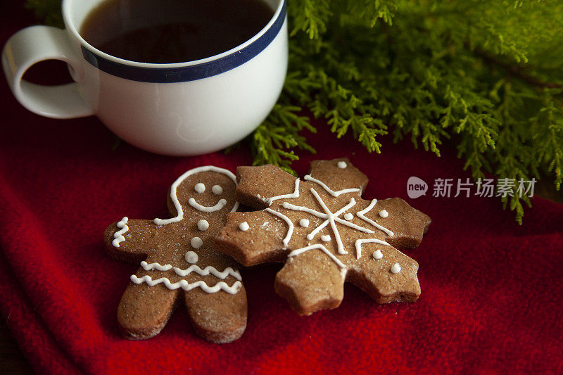 一杯茶，上面放着圣诞姜饼和雪花形状的饼干，放在脏兮兮的木头桌子上。
