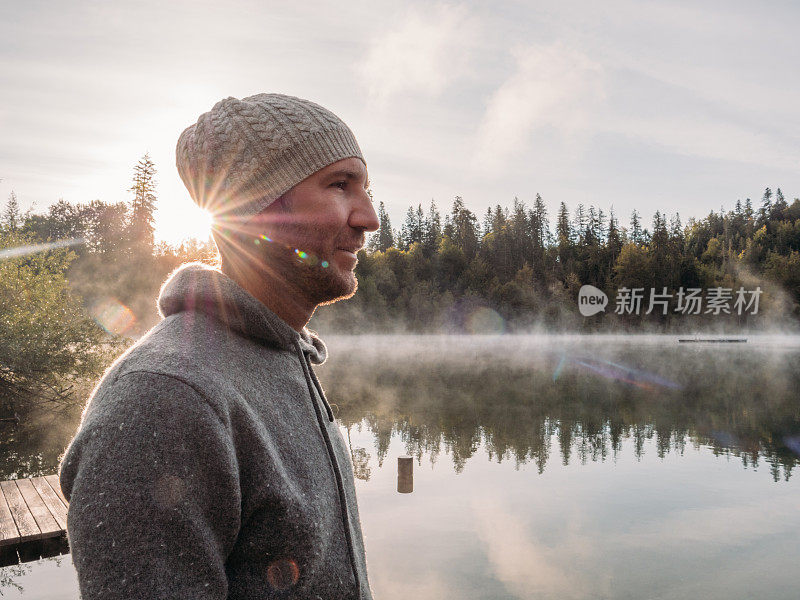 一名男子在木码头上休息，眺望着湖面