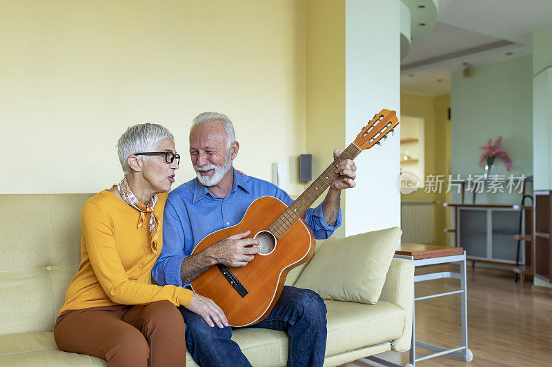 一个老人在弹吉他，他的妻子在享受音乐的节奏。