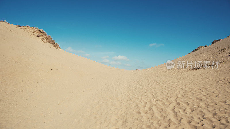 在一个阳光明媚的炎热的日子里，海岸附近有高高的沙丘
