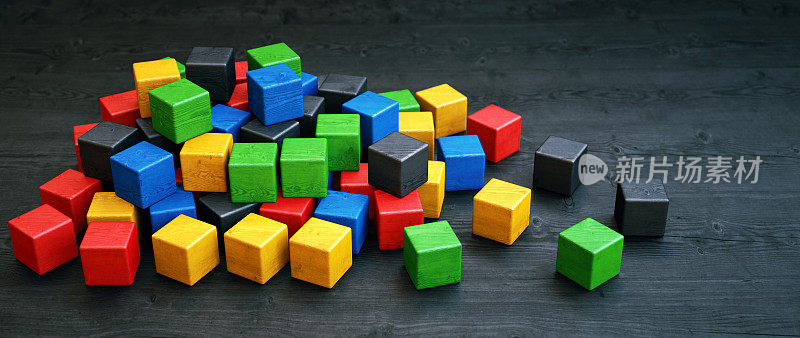 一堆彩色的立方体木块摆放在深色的木质表面上