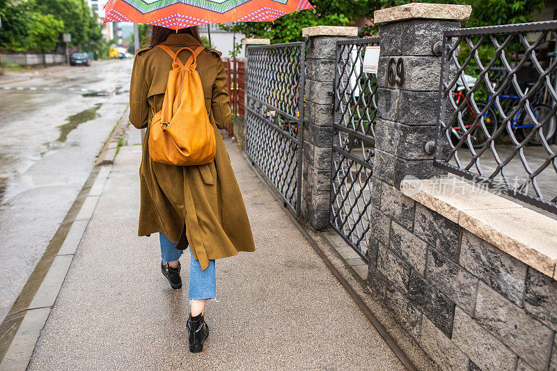 一名年轻女子在雨天撑着伞在城市里散步