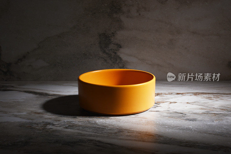 大理石背景上的橙色空陶瓷碗