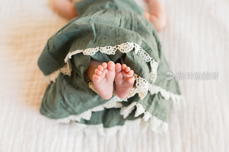 秋季新生女婴脚趾，脚和腿与舒适的奶油背景