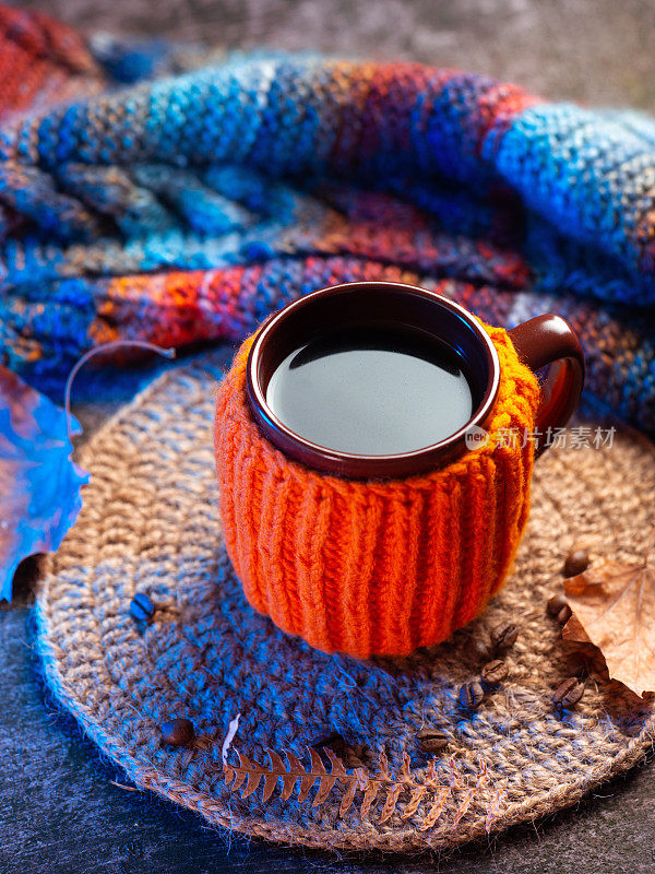 秋天作文与炎热的秋天咖啡或茶在一个杯子针织橙色毛衣。针织支架和暖和的彩色围巾