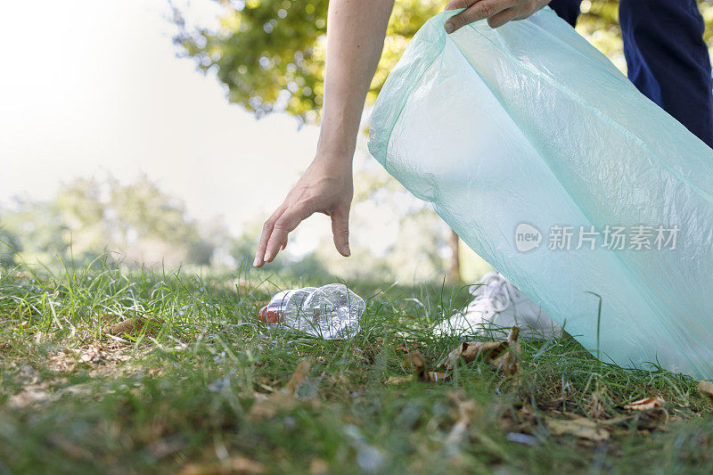 人的手捡起塑料瓶，把它放进垃圾袋