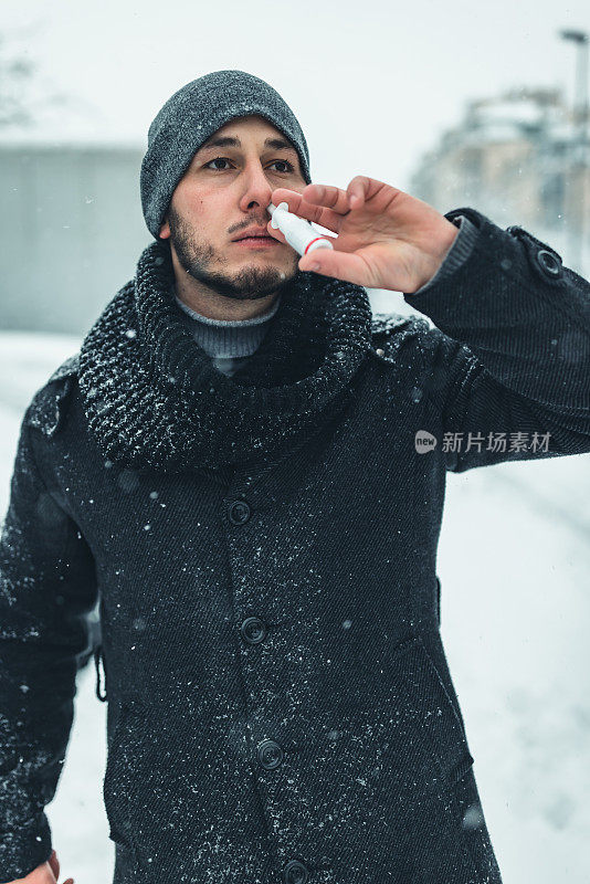 感冒和流感。一个年轻的病人在街上用喷鼻剂。