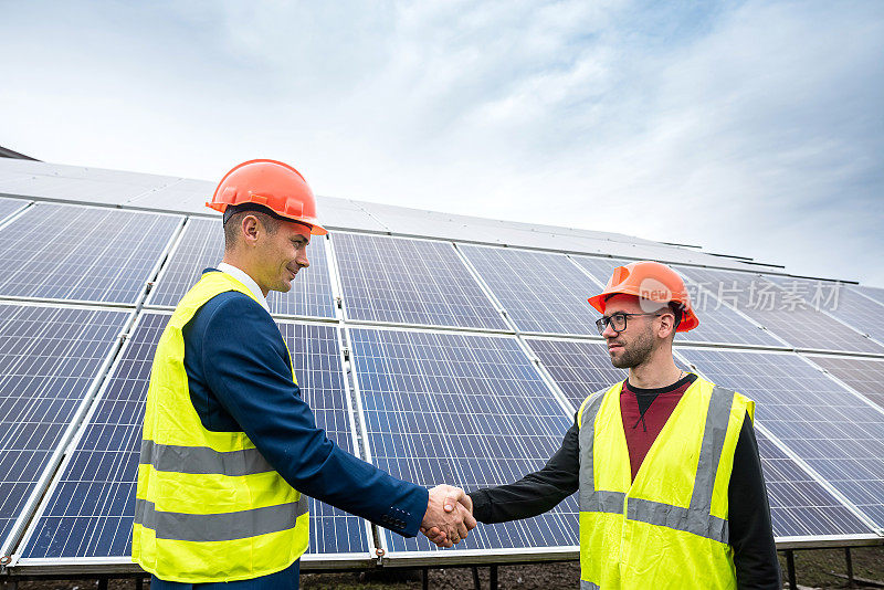 穿着工作服的工人们在开始安装太阳能电池板之前，互相握手致意。