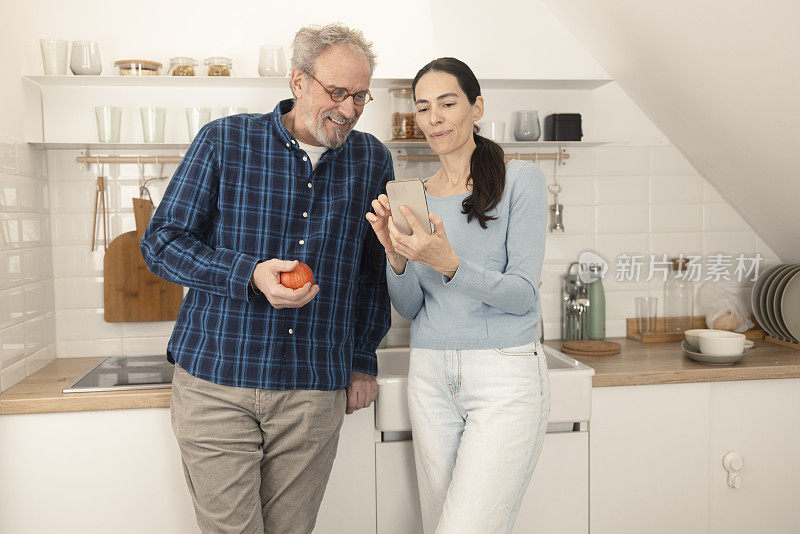 成熟的夫妇在厨房里用手机