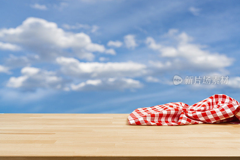 一张木桌子，铺着皱巴巴的野餐毯子，还有蔚蓝的天空