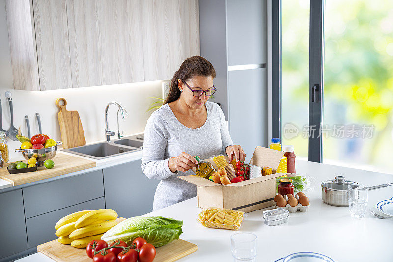 一名妇女在厨房将食物包装在捐款箱里