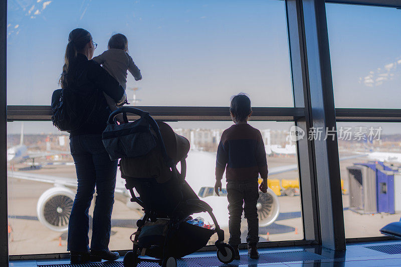小男孩，小女孩和他们的妈妈在机场透过窗户看飞机
