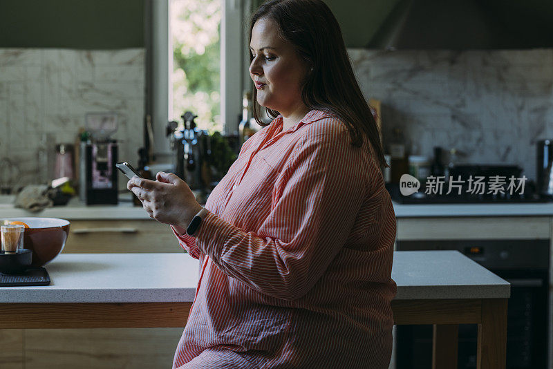 一个好奇的美丽肥胖的女商人一边在家放松一边用智能手机发短信
