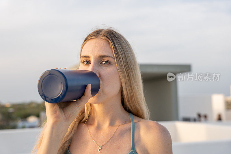 年轻女子用可重复使用的瓶子喝水的肖像