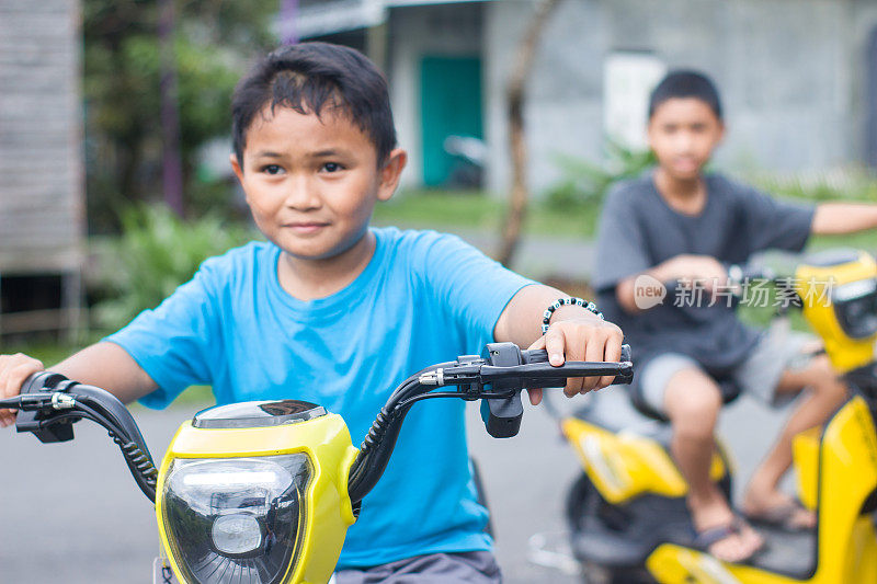男孩和弟弟在小区骑着电动车，一起出去玩