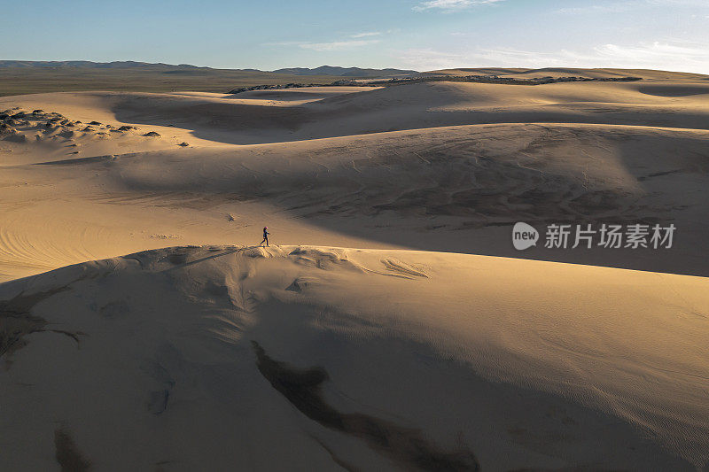 一个女人走在瓜达卢佩牧场沙丘保护区。