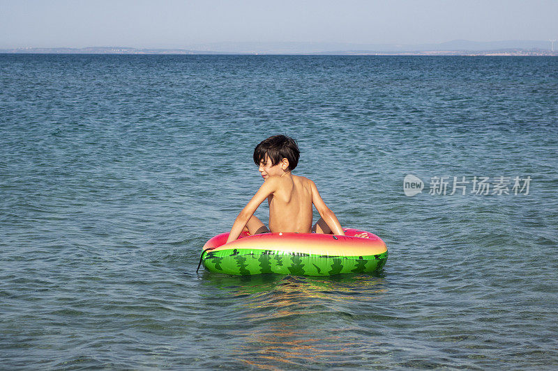 男孩在海里玩游泳圈。
