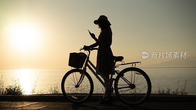 骑自行车的年轻女子在海边打电话