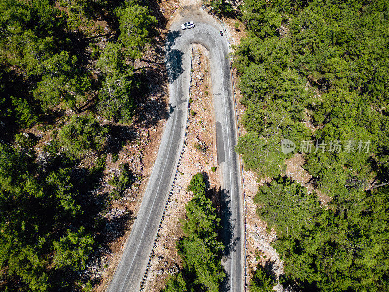 在森林山区的道路上行驶的车辆用无人机拍摄沥青弯道