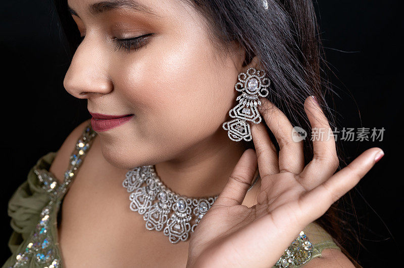漂亮的女模特展示耳环和钻石项链
