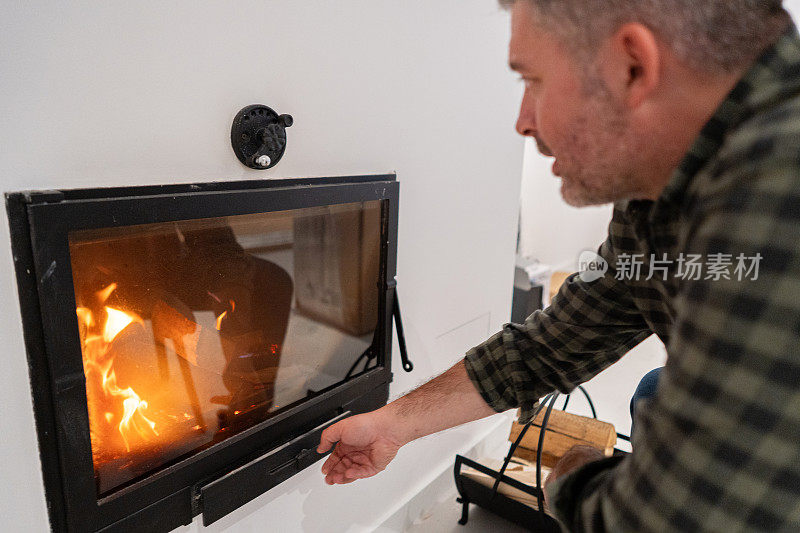 一个白人男子在壁炉里调节烟灰缸上的空气流通