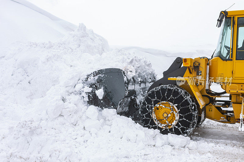 挖掘机在冬天从路上挖雪