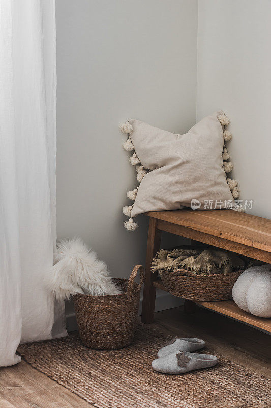 一个舒适的家庭内部——一张带有装饰性枕头的橡木长凳，一张地毯，客厅角落里的篮子里放着一条格子呢