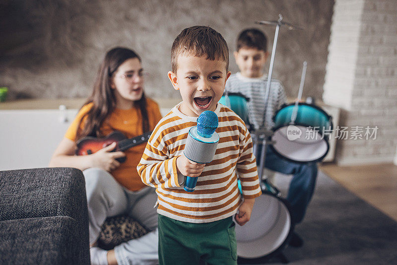 当其他孩子在演奏乐器时，一个男孩对着麦克风唱歌