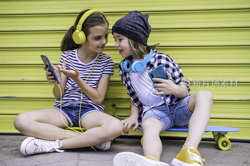 孩子们戴着耳机听音乐。的孩子。技术。副本的空间。使用手机。做有问题
