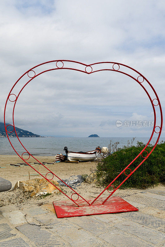 心形装置，情侣们在意大利里维埃拉度假胜地的海滩上自拍，地平线上是加里纳拉岛，意大利利古里亚萨沃纳莱格利亚
