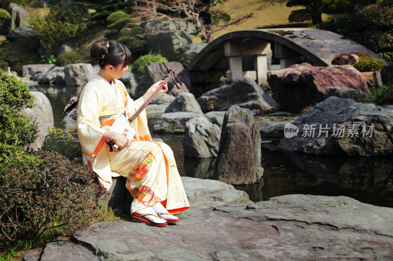 在日本花园里玩三味线的女人